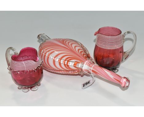 A NAILSEA GLASS SET OF NOVELTY BELLOWS, red and white striped, length 30cm and two Victorian cranberry glass jugs (3) (Condit