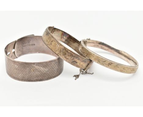 THREE SILVER BANGLES, the first a wide engine turned pattern belt style bangle, hallmarked Birmingham, a foliate pattern hing
