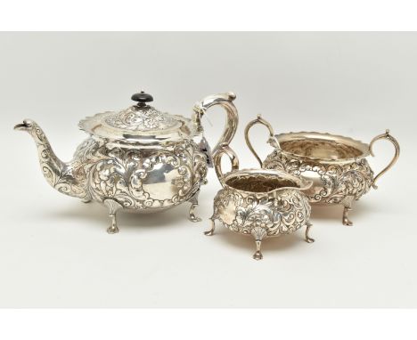 A LATE VICTORIAN SILVER THREE PIECE TEA SET OF CIRCULAR FORM WITH WAVY RIMS, ornately cast with foliate scrolls and vacant ca