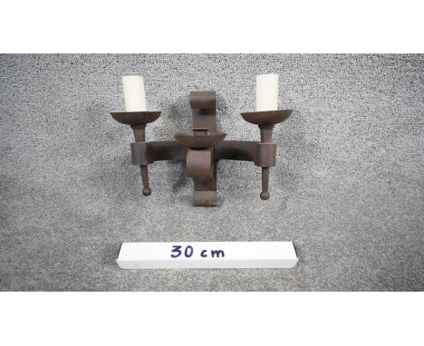An Impex refectory aged wrought iron two branch Gothic wall light with central candle holder. H.27 W.34 D.16 