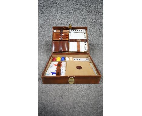 A leather cased lockable travelling gaming set, including dice, gaming pieces, cribbage, chess board and playing cards. H.18 
