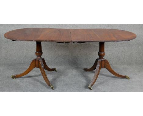A Georgian style mahogany and crossbanded D-end dining table raised on carved twin pedestal swept tripod supports. Waring and