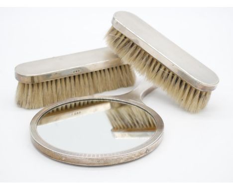 A sterling silver vintage three piece brush and mirror set, each with engine turned decoration. Hallmarked: TP, London, 1958.