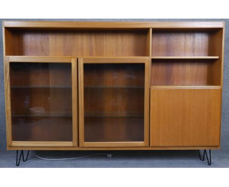 A vintage McIntosh teak bookcase cabinet with interior light standing on metal hairpin supports with maker's label. H.122 W.1