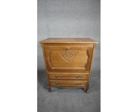 A Continental light oak drinks cabinet with carved fall above two drawers on cabriole supports. H.101 W.80 D.43 