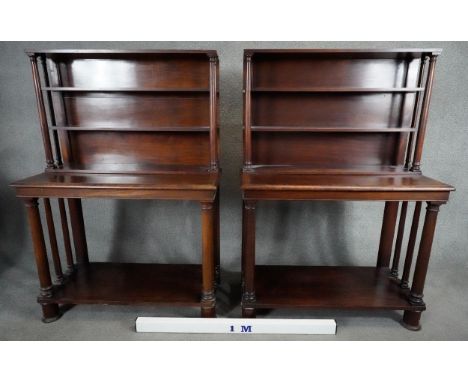 A pair of mid 19th century mahogany bookcases with open upper sections above console bases raised on circular supports united