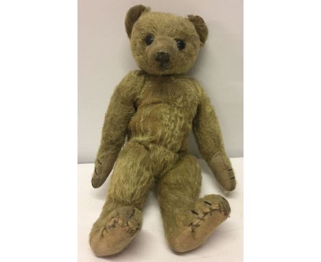 A c1910 German teddy bear, possibly Steiff. Well loved golden mohair, straw filled, boot button eyes, long snout, hump and lo