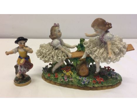 A porcelain figurine of two young girls on a see-saw together with a ceramic drummergirl - a/f.