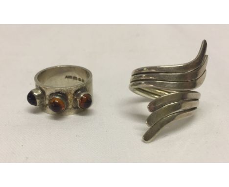 2 modern silver rings, one set with amber - size K1/2, and the other in a cross-over design - size O.