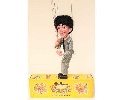 Pelham: A boxed Pelham Puppet, Pop Singer, based on The Beatles, holding two drumsticks, in a grey suit outfit, appears in go