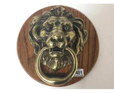 A large solid brass 19th Century door knocker in the form of a lion. Mounted on a later plaque. 22x27cm.