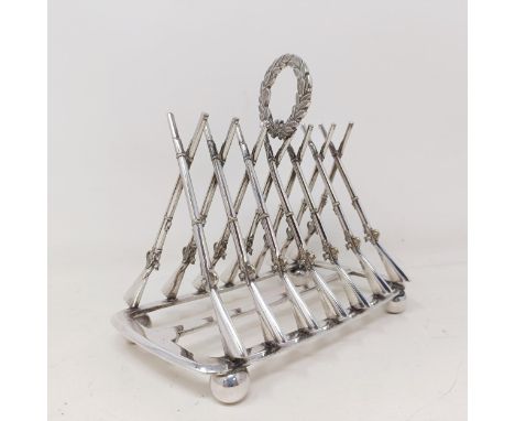 A late Victorian silver plated novelty toast rack, the division in the form of shotguns, 16 cm wide