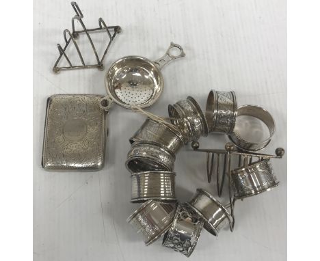 A collection of silver wares comprising a pair of four section toast racks, a silver cigarette case with engraved scrolling d