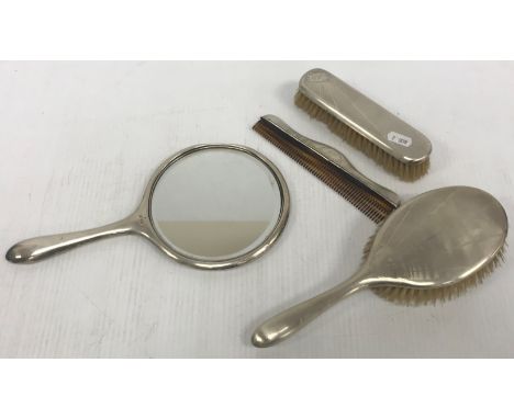 A George V four-piece silver-backed dressing table set with engine turned sun ray decoration comprising handled brush, handle