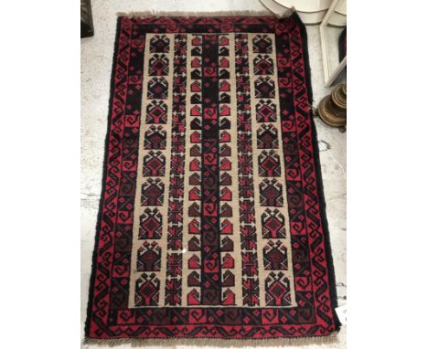 A Belouch rug, the central panel set with rows of repeating geometric design on a mushroom ground, within a stepped red and b
