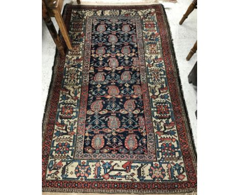 A Mahal rug, the central panel set with stylised hook motifs on a blue ground, within a red and cream stylised scrolling foli