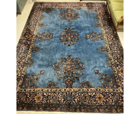 A Persian carpet, the central panel set with scrolling floral sprays on a blue ground, within a stepped blue, cream and green