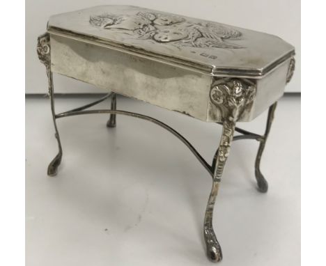 An Edwardian silver ring box, the rectangular cover decorated with five cherubs opening to reveal a fitted interior over a pl