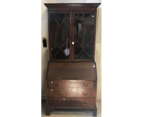 A mahogany bookcase cabinet in the Georgian style, the moulded dentil cornice over an astragal glazed door and panelled doors