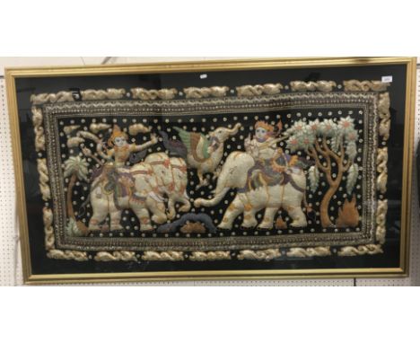 A 20th Century Indonesian embroidered and sequinned panel depicting "Two figures and elephants with flying mythical beast amo