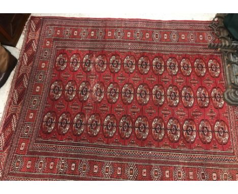 A modern Tekke Bokhara rug, the central panel set with stylised elephant foot medallions on a red ground, within a stepped re