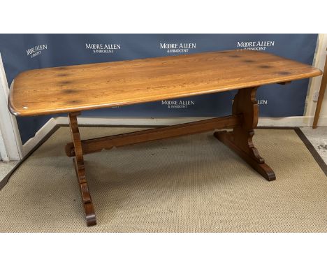 An Ercol elm rounded rectangular dining table on trestle end supports united by a centre stretcher 184 cm long x 89 cm wide x