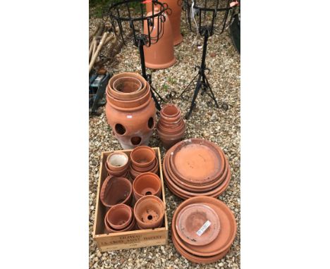 A collection of terracotta plant pots and saucers including a strawberry pot together with two black painted wrought iron pla
