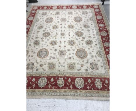 A Ziegler type carpet, the central panel set with scrolling foliate decoration on a cream ground, within a stepped red and cr