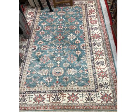 An Afghan Kazak rug, the central panel set with repeating stylised floral motifs on a pale blue ground, within a stepped crea