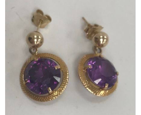 A pair of yellow metal mounted amethyst drop earrings, the stones approx 5 carat, approx 1.2 cm diameter, within a latticewor