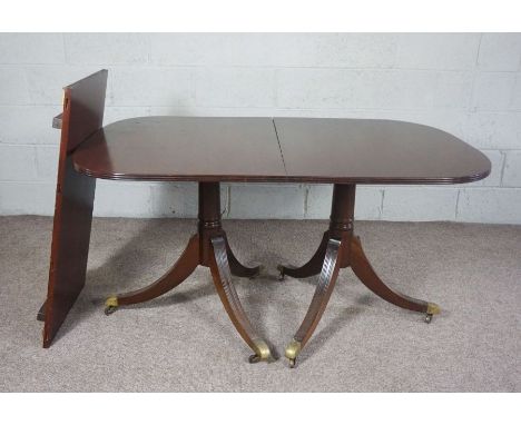 A George III style twin pillar mahogany extending dining table, circa 1900, with reeded top, additional leaf, and set on two 