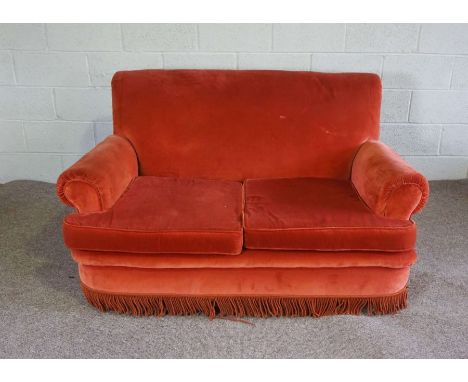 A small red two seat sofa, with scrolled arms and tassel fringe, 153cm wide; together with three embroidered cushions (4)