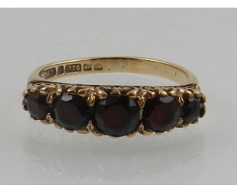 A 9 carat yellow gold and garnet ring, set five round cut graduated garnets.