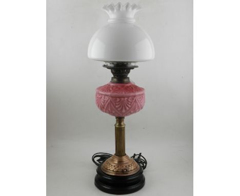 A VIctorian oil lamp, having opaque white shade and pink glass reservoir above reeded brass column, mounted on circular ogee 