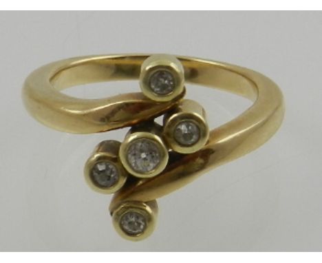 A 14 carat yellow gold and five stone diamond cross over ring. 