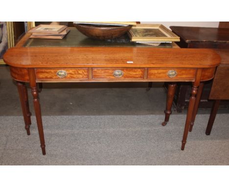 A satinwood bow fronted hall table, fitted three drawers, raised on turned tapering fluted supports, terminating in peg feet,