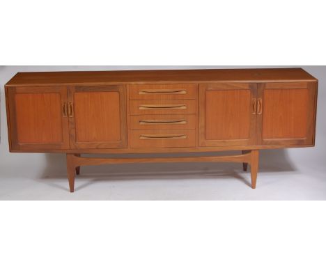 A 1960s G-Plan teak long sideboard, having four central drawers flanked by twin recessed panel cupboard doors, all with integ