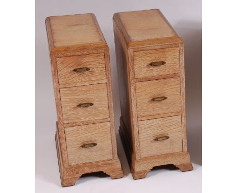In the manner of Heals - A pair of Art Deco limed oak three drawer bedside chests, each having a moulded top, stylised floral