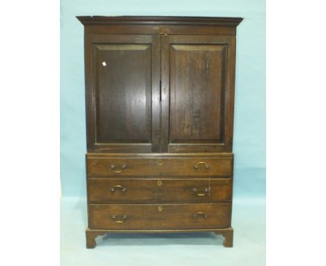 An antique oak linen press/wardrobe, having a pair of panel doors above a false drawer and two long drawers, 122cm wide, 196c