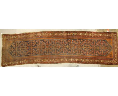 An early-20th century Oriental corridor carpet, profusely-decorated with stylised flowers and birds, on a dark blue ground wi