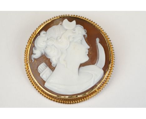 Shell cameo 9ct yellow gold circular brooch, the cameo depicting the head of Artemis with bow and arrow, rubover set, rope tw