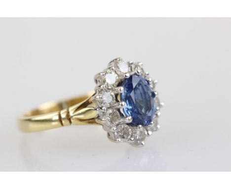 Sapphire and diamond 18ct yellow and white gold set cluster ring, the oval mixed cut blue sapphire measuring approx 7.6mm x 6