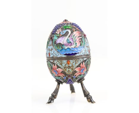 20th century Russian enamelled silver egg shaped trinket pot raised on three hoof legs, four cabochon cut garnets set to the 