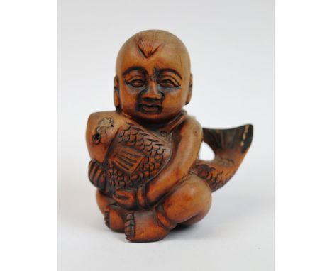 Wooden Netsuke of boy holding fish - signed to base 