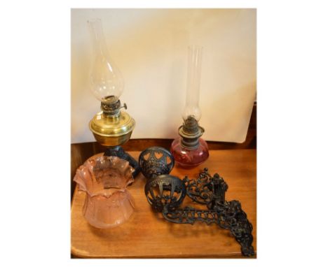 Cast iron and brass paraffin lamp, pair of swing wall lamp fittings, cranberry reservoir with chimney, and tinted shade  