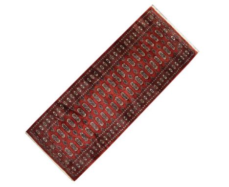 Tekke Turkoman or Belouch-style wool runner, the brick-red field decorated with two rows of twenty-two guls separated by hook