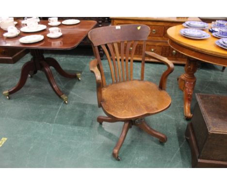 Edwardian oak swivel office chair, raised on brass and ceramic castors.  Height to back of chair 85 cm, width across arms 57 