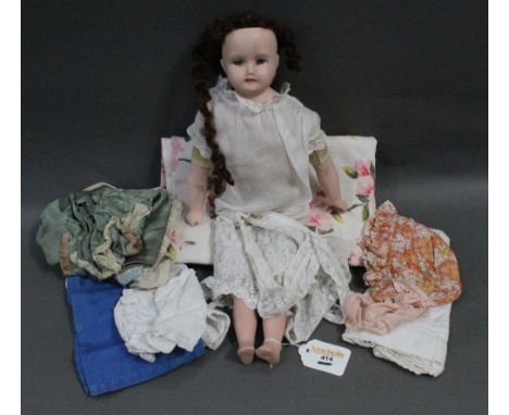 A late Victorian/Edwardian bisque headed doll, clothed and with spare clothing (709 12/22)