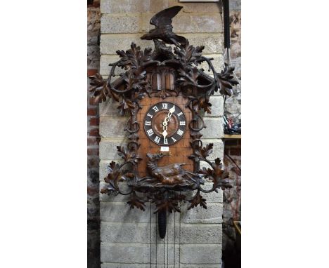 A large late 19th century Black Forest musical cuckoo wall clock, surmounted by a carved eagle, the three train movement flay