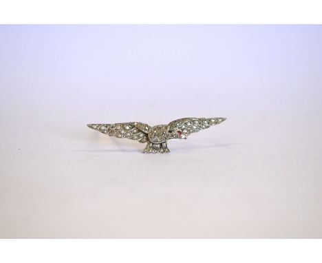 A diamond-set brooch in the form of an eagle with outswept wings, set overall with rose cut diamonds and with cabochon ruby e